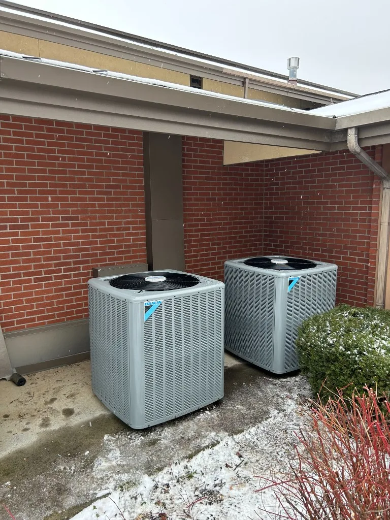 Pair of Daikin condensers mounted at a Palouse commercial building with brick exterior and light snow on the ground