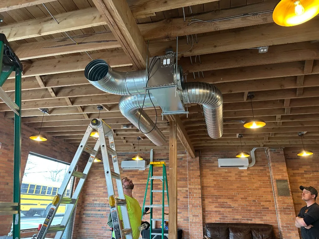 Interior of a Palouse cigar lounge during install with two Unlimited technicians running spiral duct and mounting ductless mini-split heads